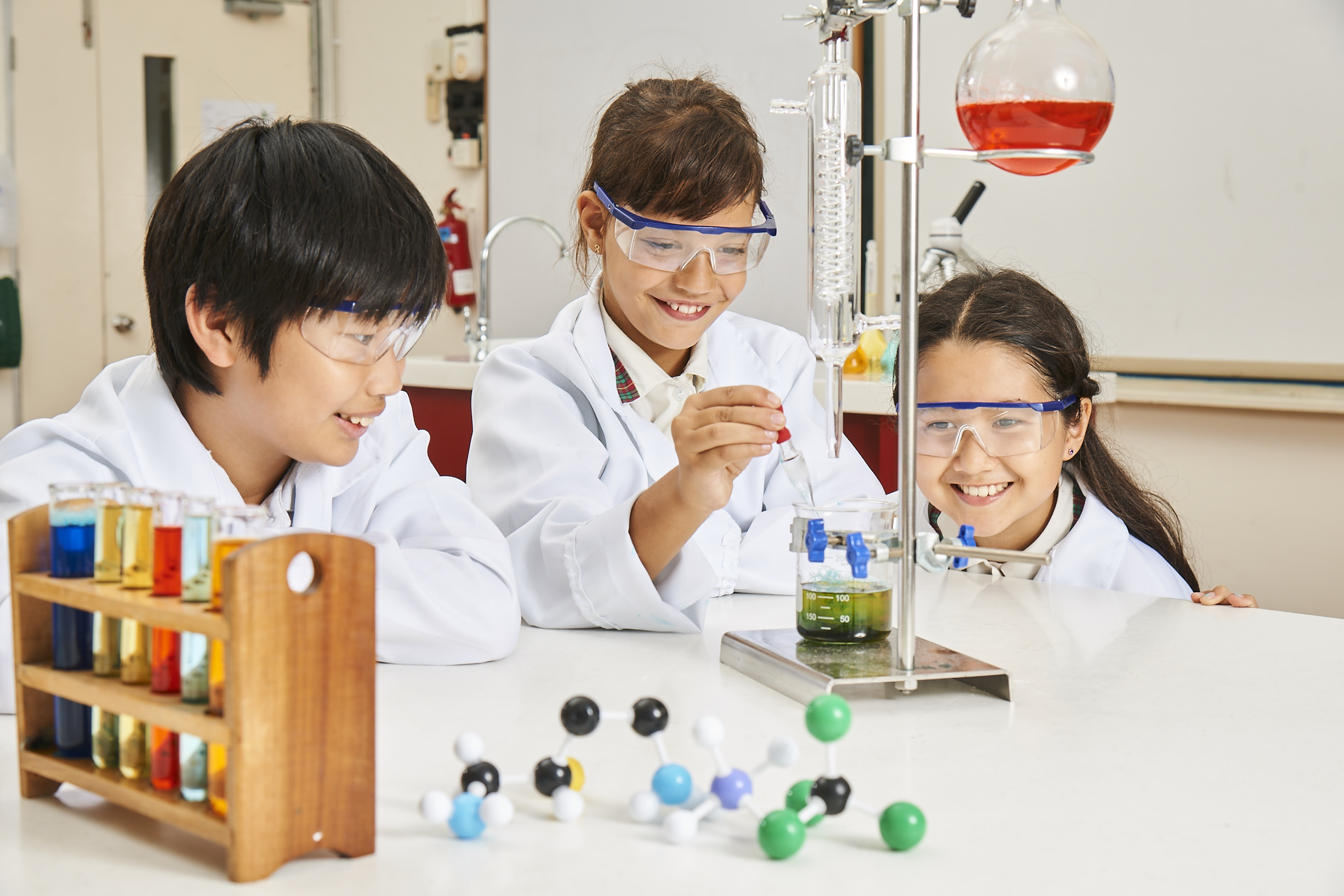 EtonHouse Riyadh - Children wearing lab coats doing a science experiment in a classroom.