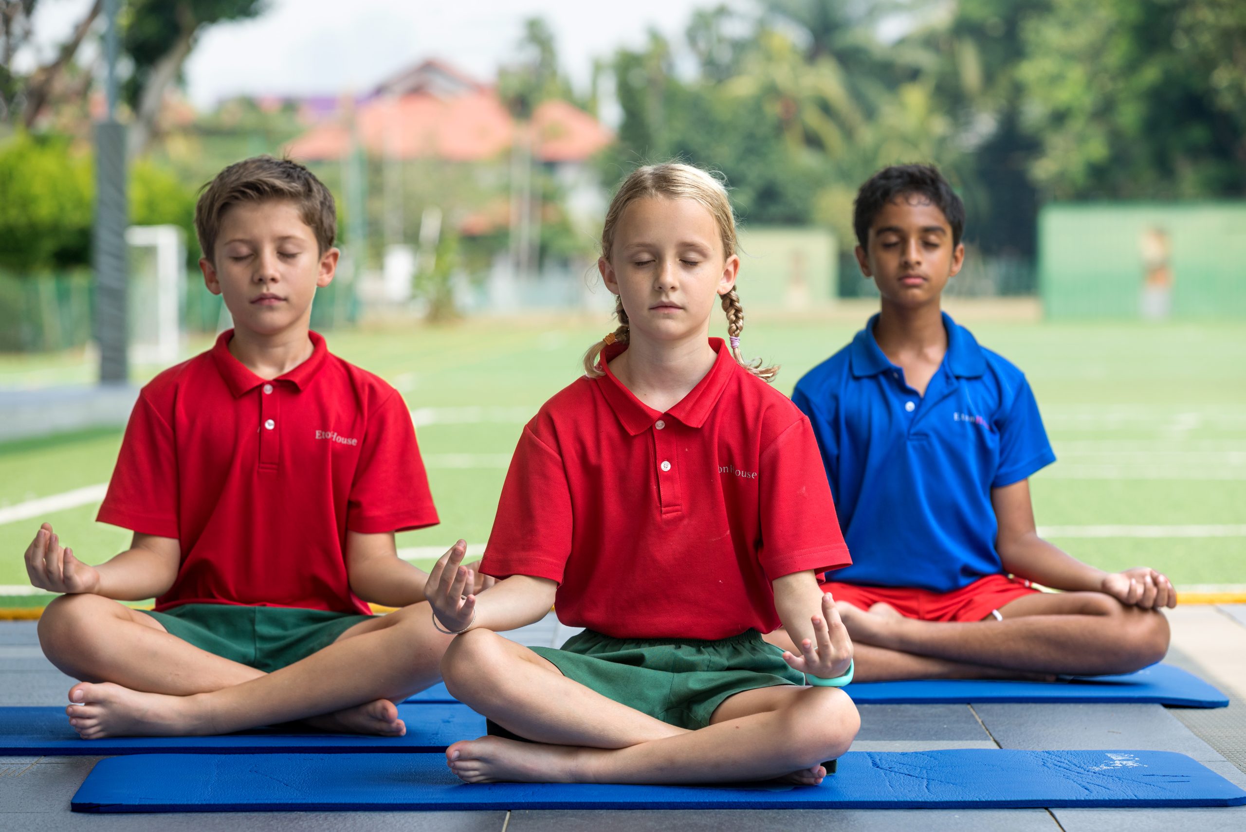 EtonHous Riyadh students in uniform performing yoga on a playground