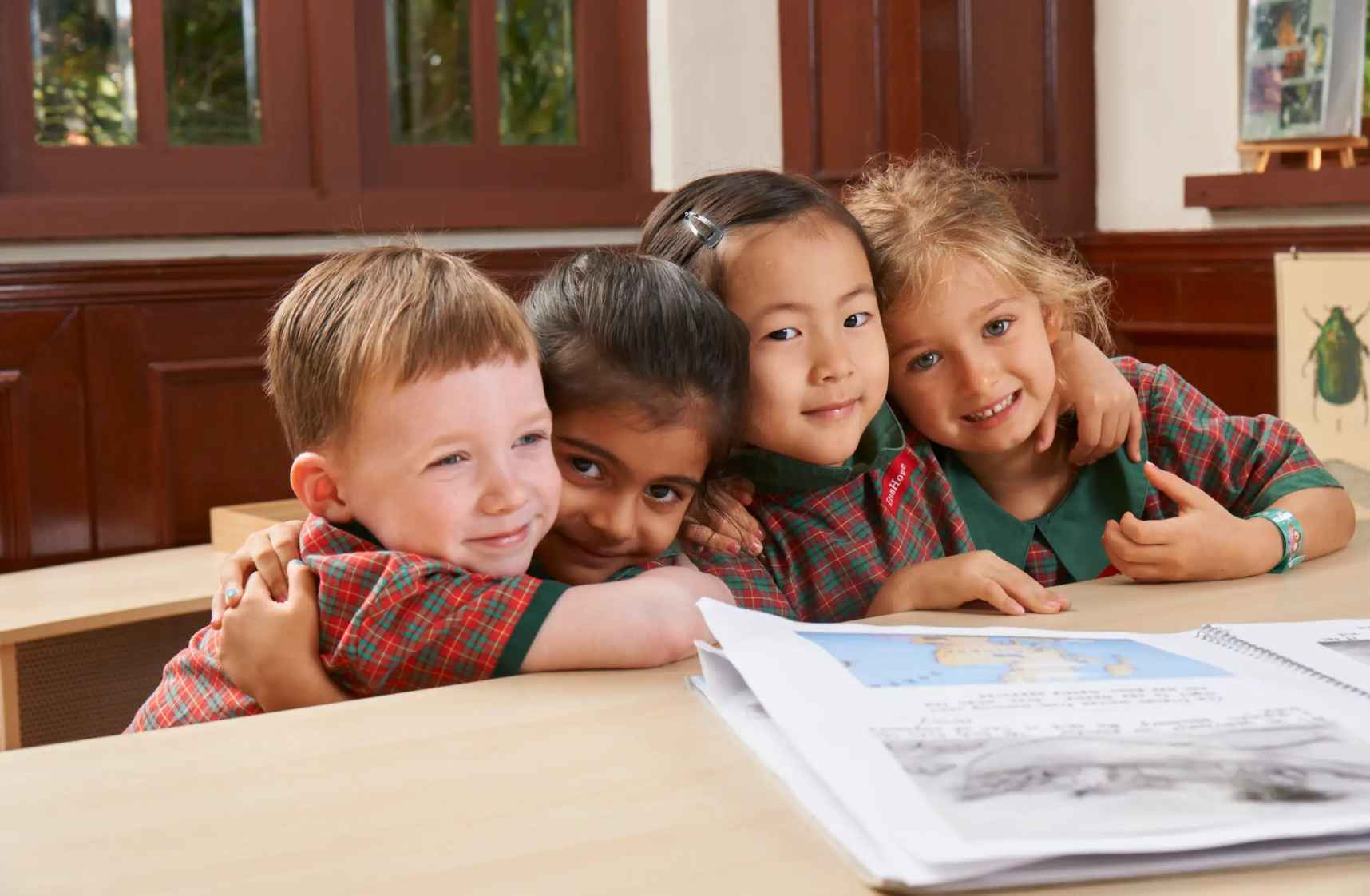 EtonHouse Riyadh - A group of preschoolers hugging each other while sitting on a table