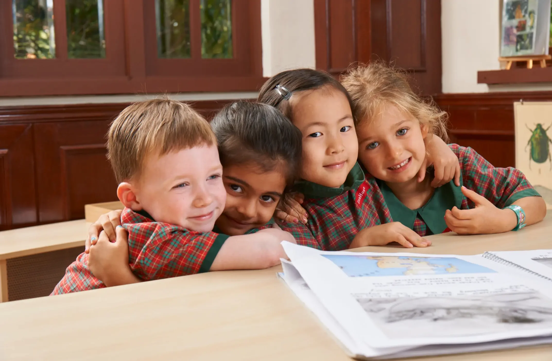 EtonHouse Riyadh - A group of preschoolers hugging each other while sitting on a table